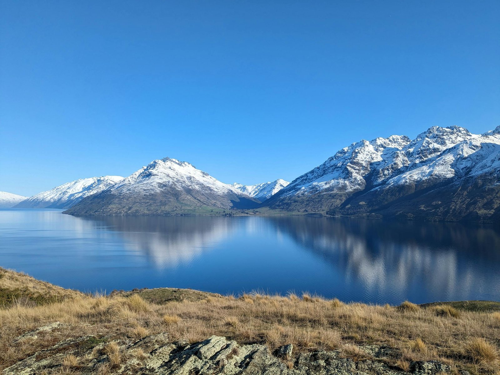Breathtaking scenery of snow-capped mountains reflected in a serene lake at Jacks Point, Otago, New Zealand.